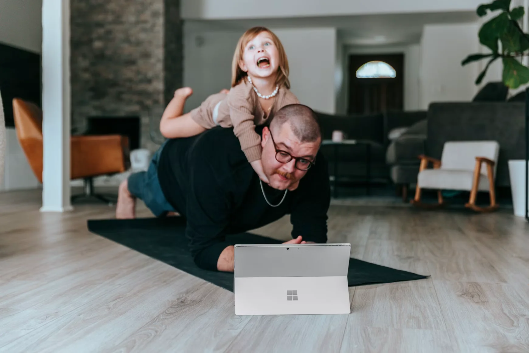 Coach working out at home on a yoga mat with a laptop open to coaching software