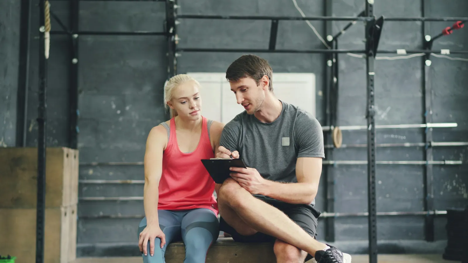 Coach and client reviewing a month of training progress together on a laptop, the monthly review meeting that turns check-in data into a conversation