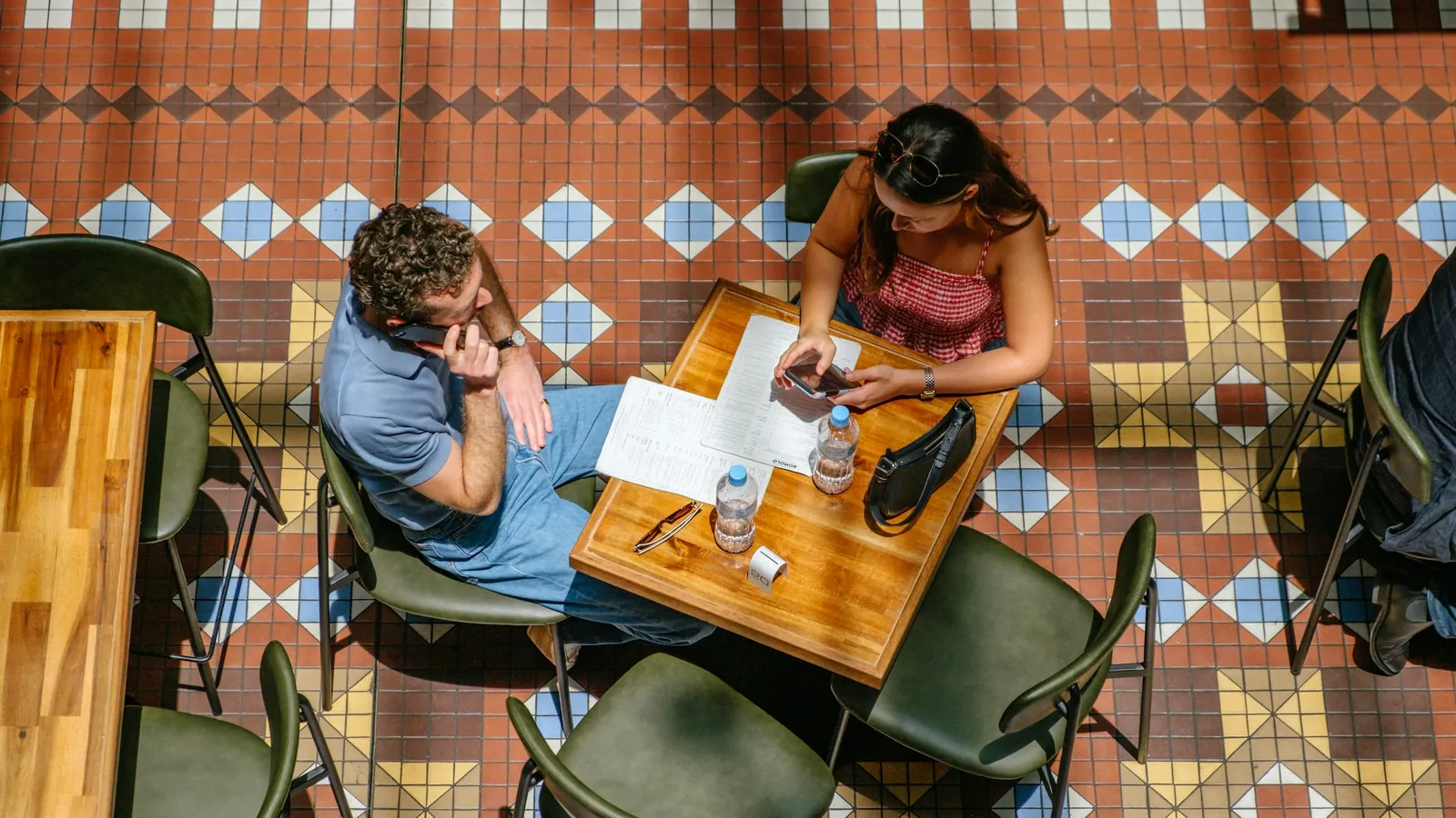 Two people in conversation across a cafe table, the one-to-one conversation where a coach asks a client for a referral