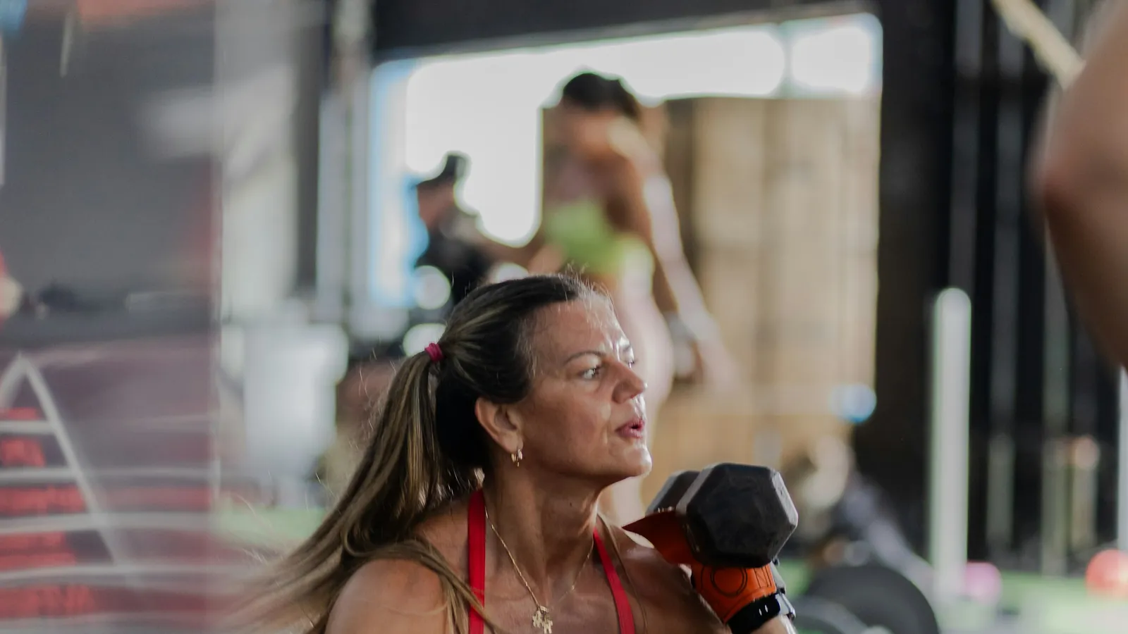 A woman pressing a dumbbell in a gym, the strength work that supports muscle and bone through the menopause transition