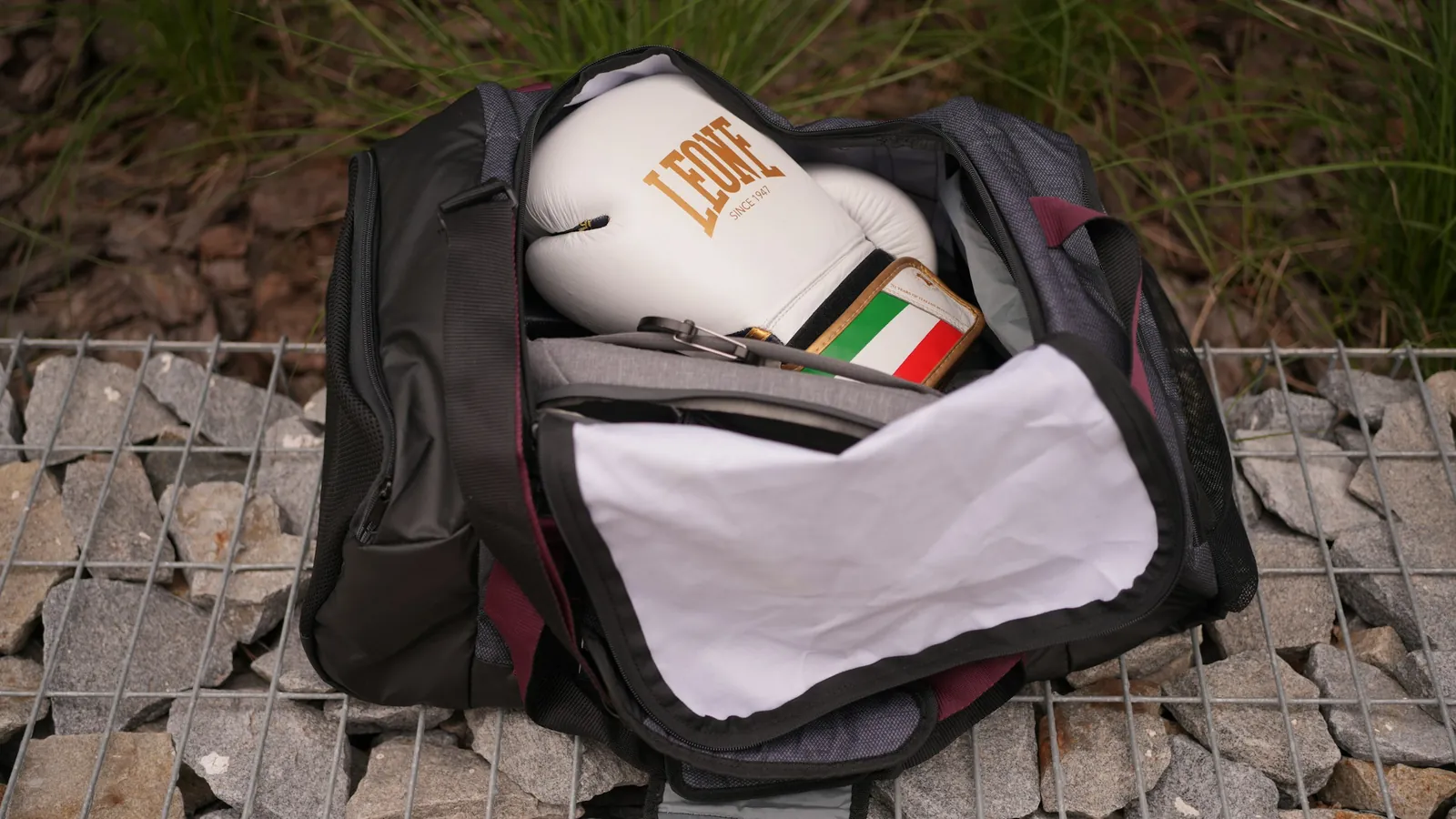 A training towel and a water bottle beside a phone showing a branded coaching app, the fitness merchandise clients actually use weekly