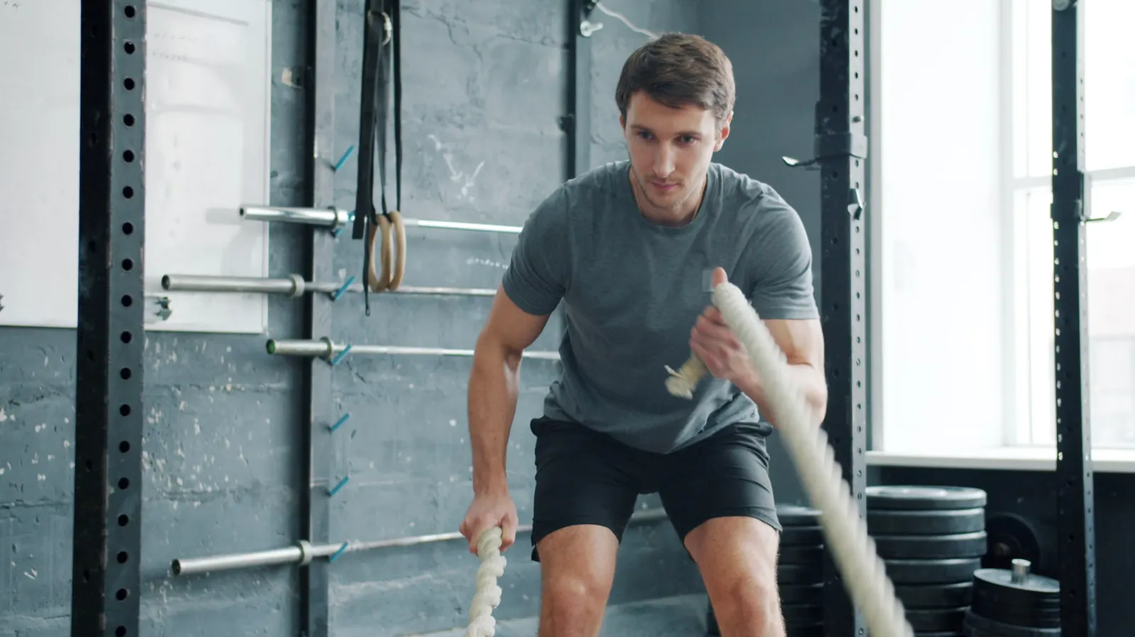 Personal trainer working battle ropes in a strength gym