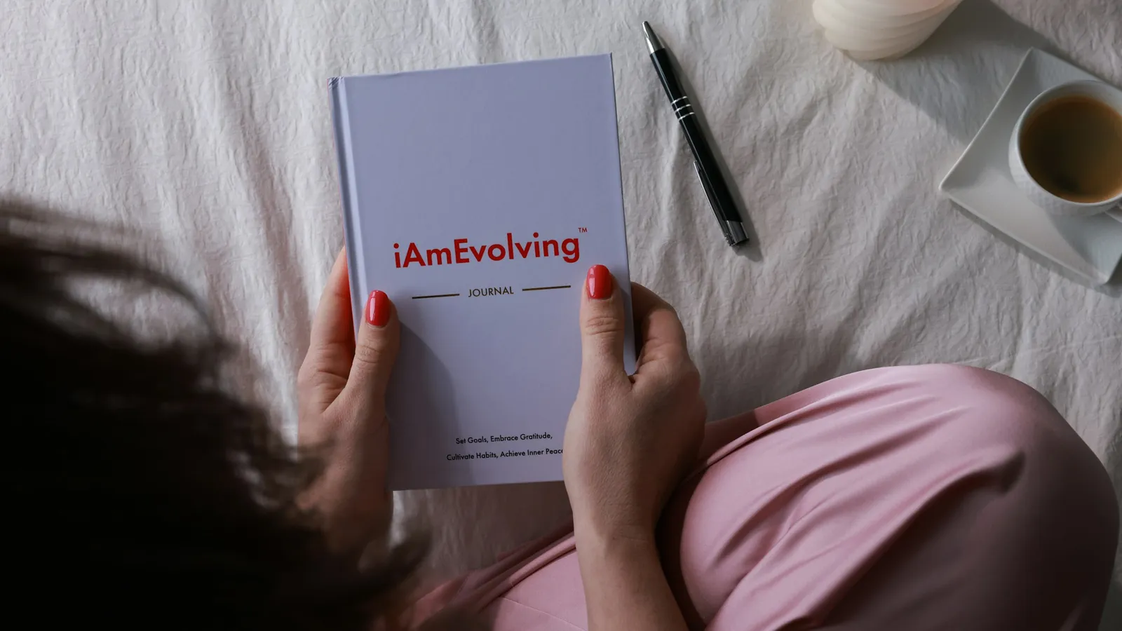 An open journal with a pen beside it on a soft surface, the written weekly record a coach reads across a month of menopause client check-ins