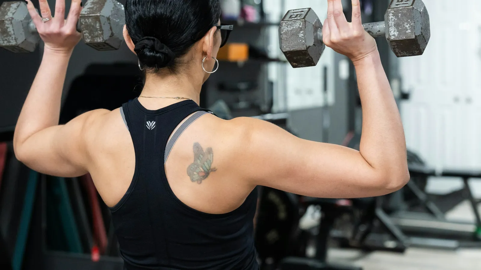 A woman training with dumbbells in a gym, the strength work a menopause coach programmes through the transition