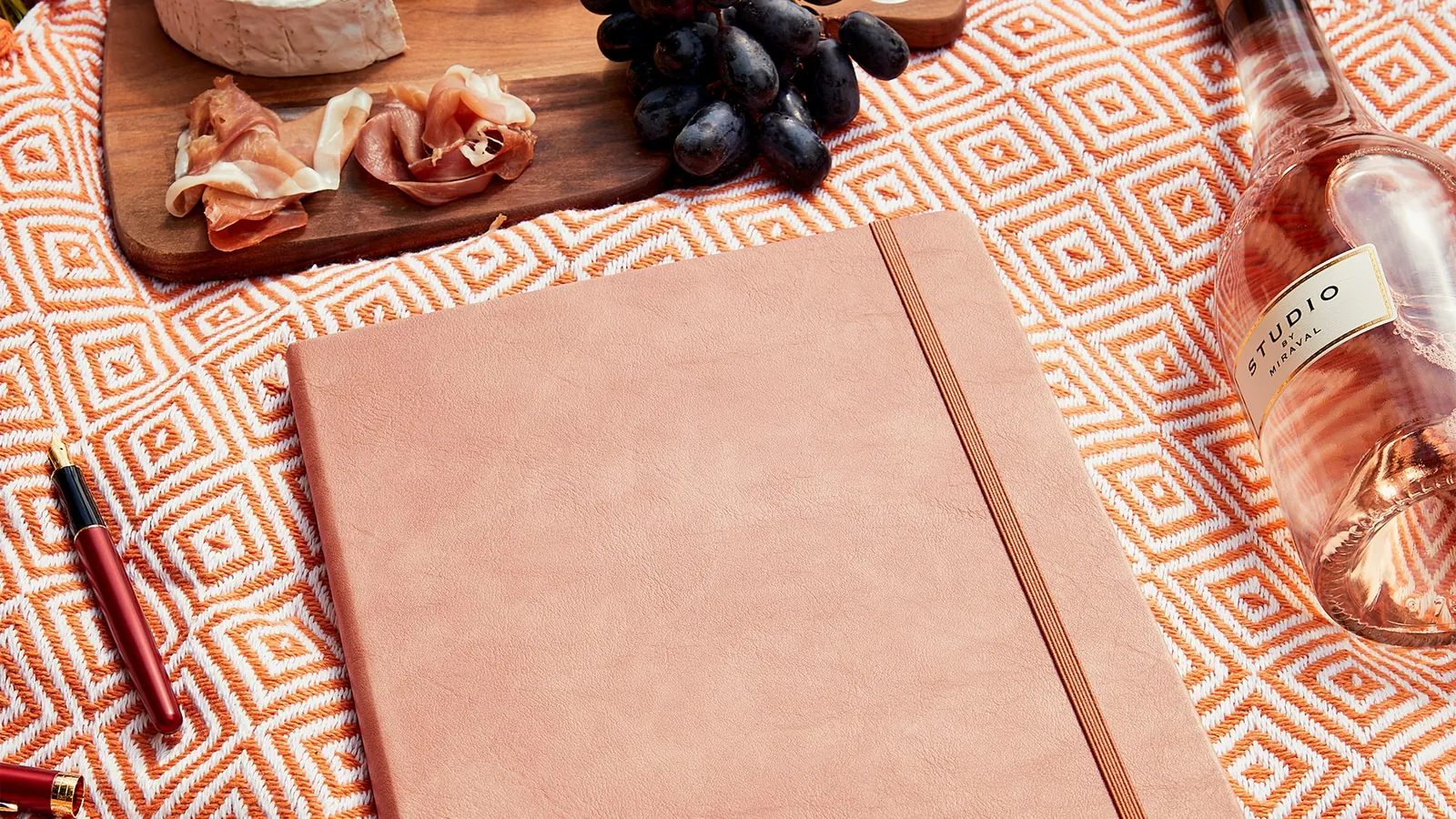 A food journal open beside a spread of fresh food on a table, the notebook at the heart of a nutrition coach's weekly check-in
