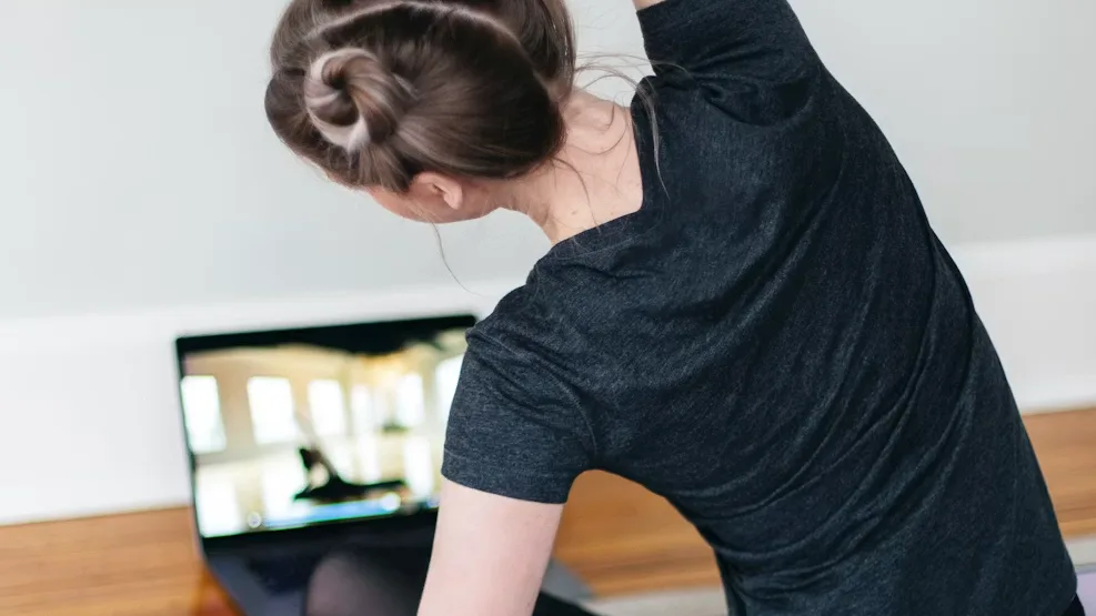 New online coaching client following her first workout from a laptop at home on an exercise mat