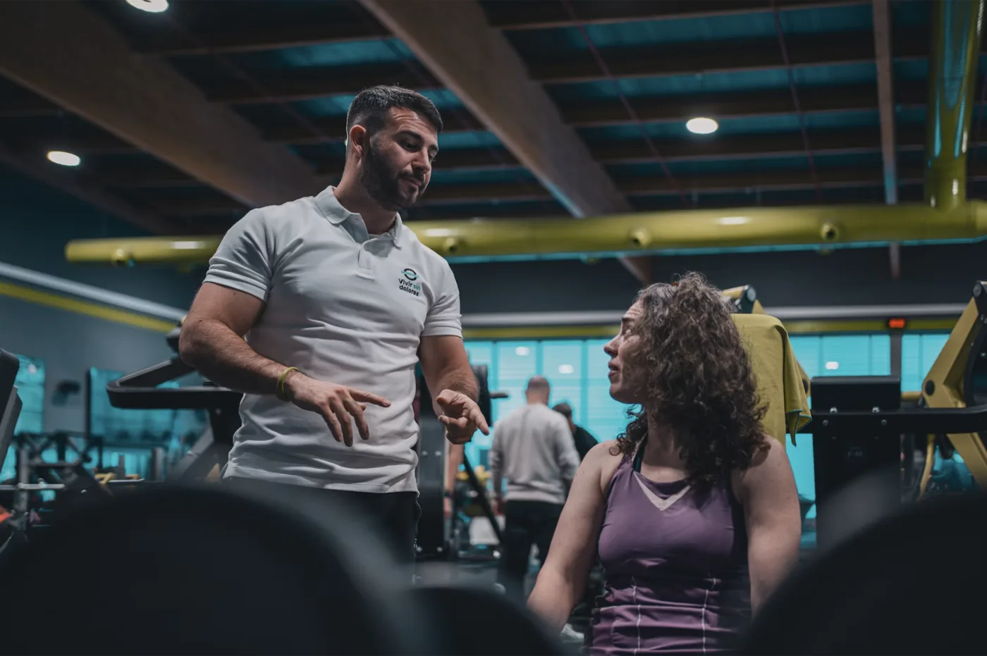 Personal trainer talking through a plan with a client between sets on a gym floor