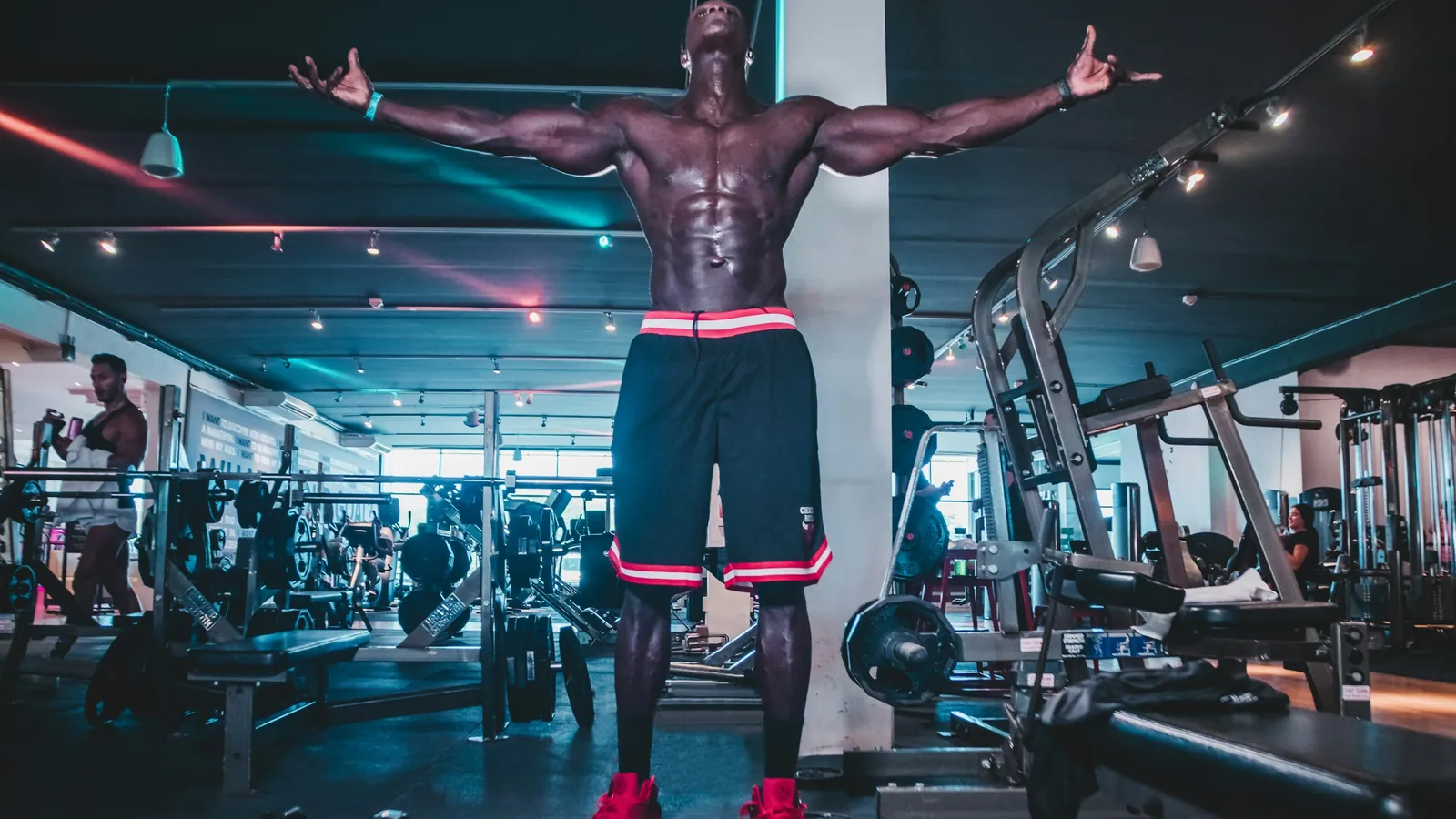 A physique competitor holding a pose under stage lighting during a bodybuilding competition