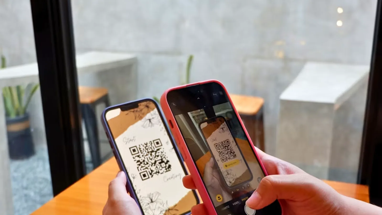 One phone scanning a QR code shown on another phone across a cafe table, the way a client scans a coach's sign-up code to join their group