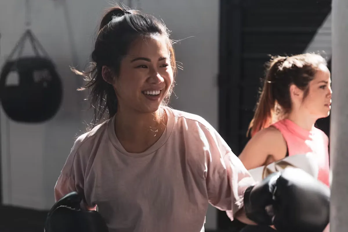 Smiling woman in a boxing class at a gym wearing boxing gloves