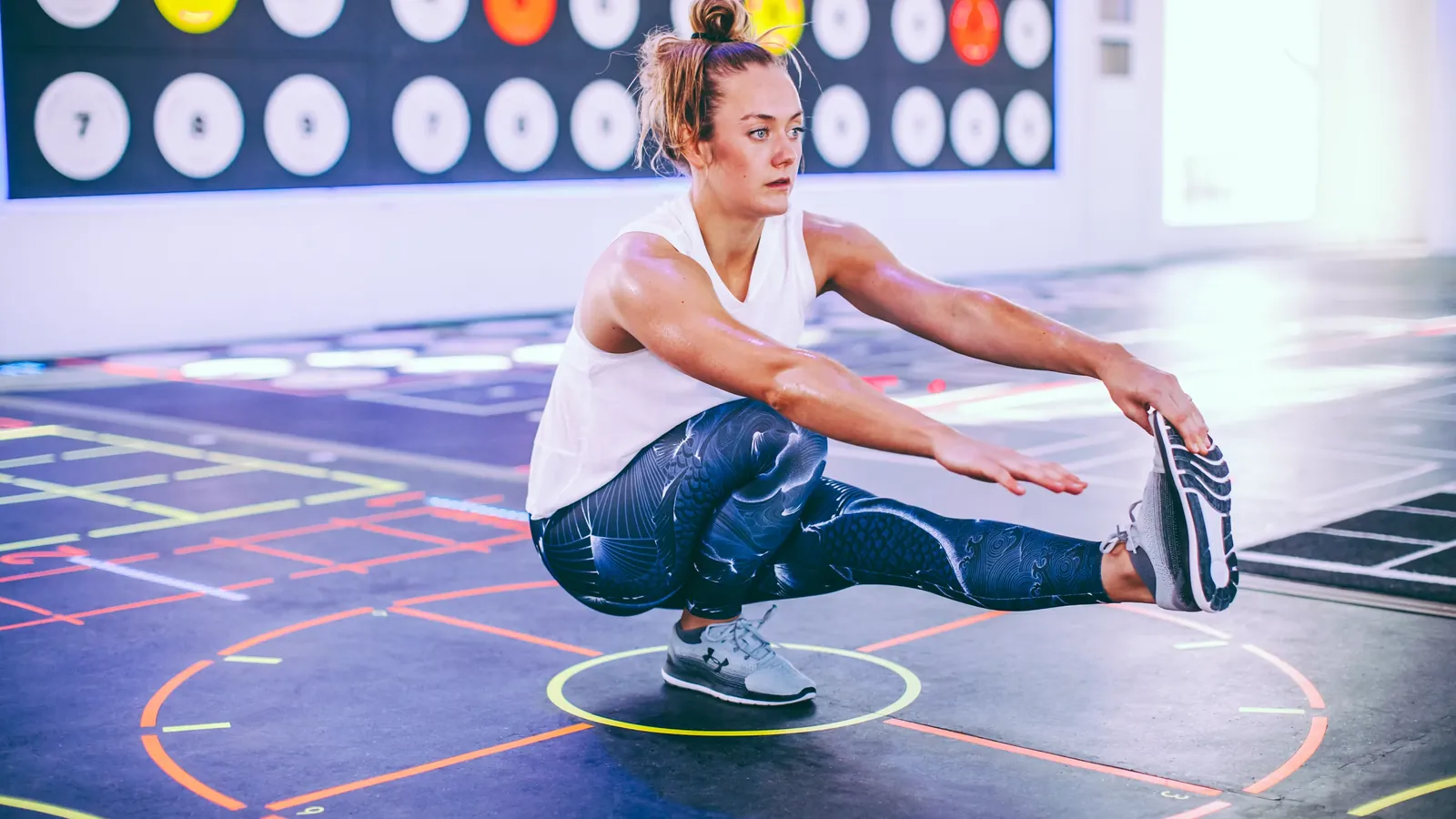 Athlete performing a single-leg balance drill on a gym floor, the kind of uncommon prehab exercise coaches add beneath the main lifts